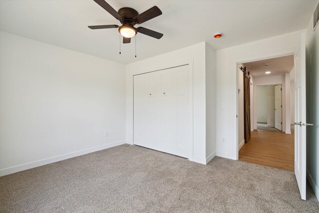 unfurnished bedroom featuring ceiling fan, a closet, and light carpet