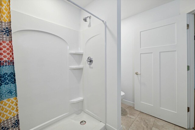 bathroom with toilet, tile patterned flooring, and tiled shower