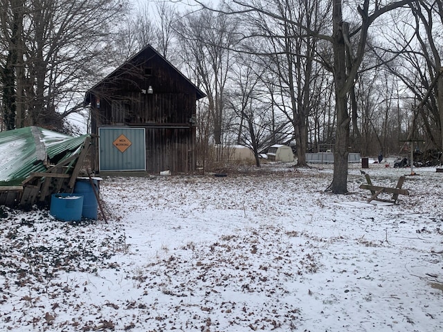 yard layered in snow featuring an outbuilding