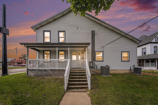 view of front of property featuring a porch, a yard, and central air condition unit