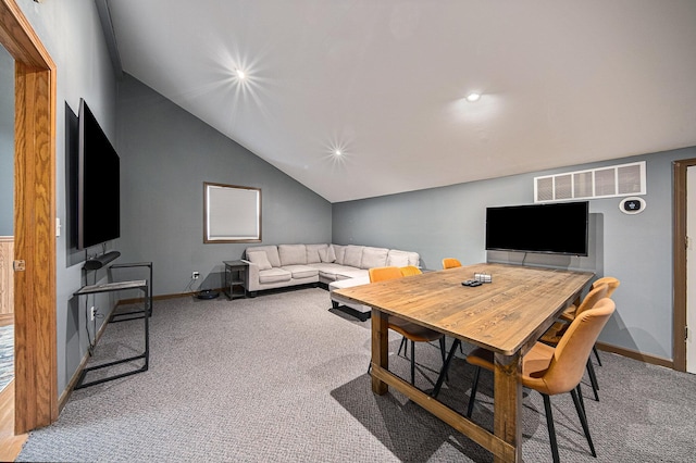 carpeted dining space with vaulted ceiling