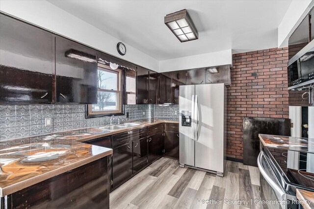 kitchen featuring sink, stainless steel appliances, backsplash, dark brown cabinets, and light wood-type flooring