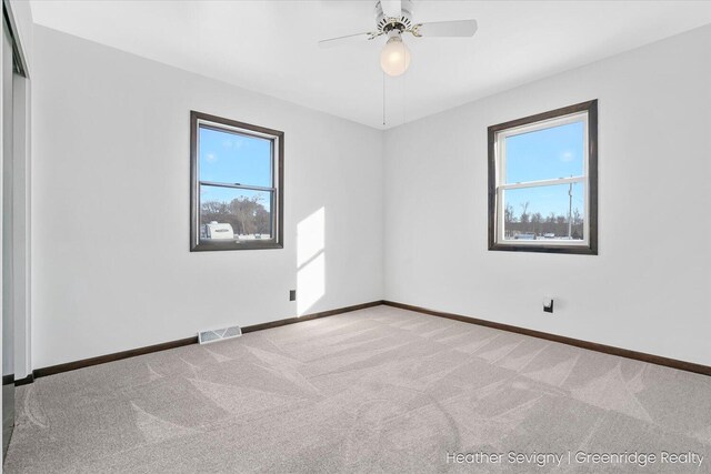 spare room featuring light carpet, ceiling fan, and a healthy amount of sunlight