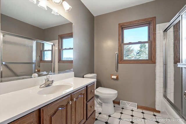 full bathroom featuring vanity, toilet, a wealth of natural light, and bath / shower combo with glass door