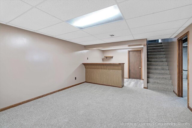 basement featuring a paneled ceiling and light carpet