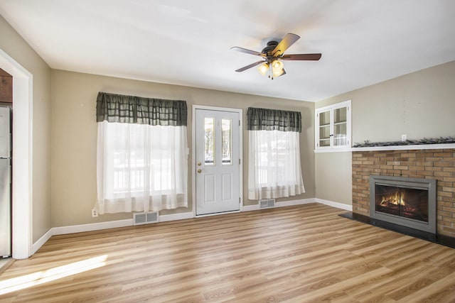 unfurnished living room featuring a fireplace, ceiling fan, and light hardwood / wood-style flooring