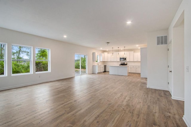 unfurnished living room with baseboards, light wood-type flooring, visible vents, and recessed lighting