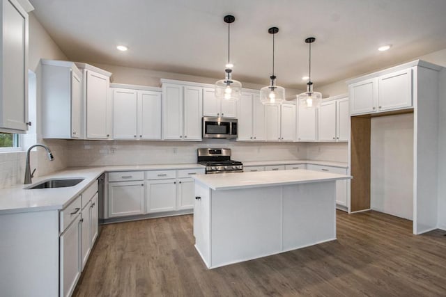 kitchen with sink, a center island, pendant lighting, stainless steel appliances, and white cabinets