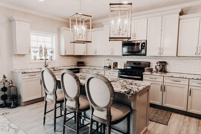 kitchen with white cabinetry, hanging light fixtures, a kitchen breakfast bar, gas stove, and a kitchen island