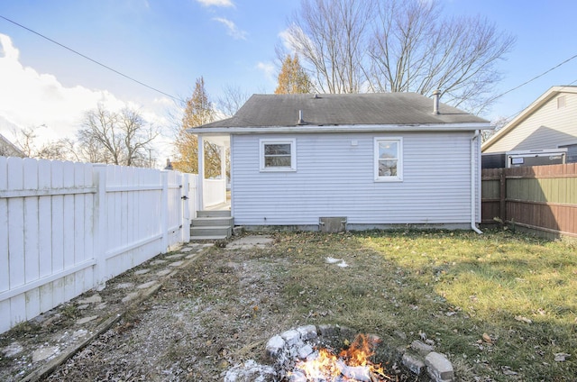 rear view of house with a lawn and an outdoor fire pit