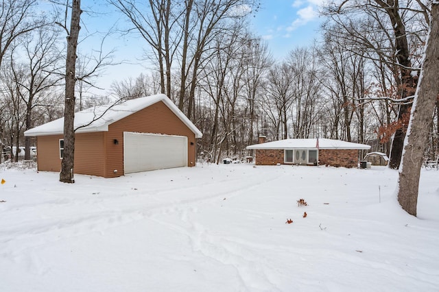 snowy yard with a garage and an outdoor structure