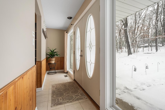 entryway featuring light tile patterned floors and wooden walls