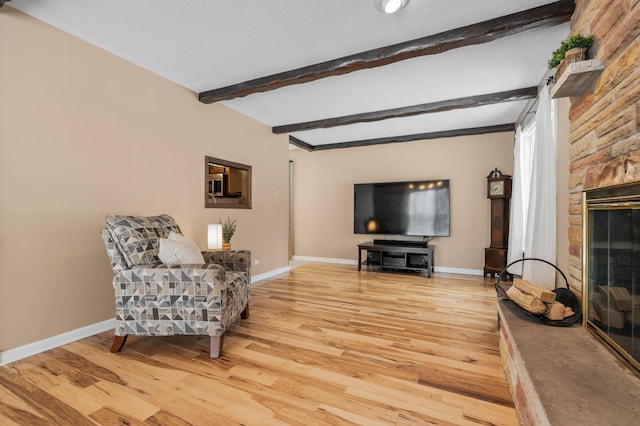 sitting room featuring beam ceiling, light wood-type flooring, and a fireplace