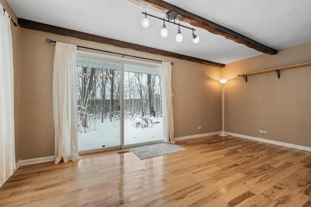 interior space with beam ceiling, light hardwood / wood-style floors, and a textured ceiling