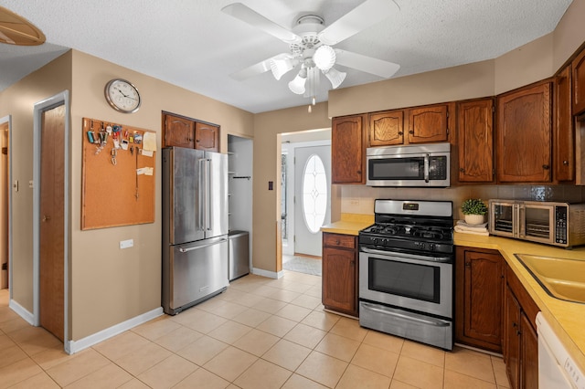 kitchen featuring ceiling fan, light tile patterned floors, a textured ceiling, and appliances with stainless steel finishes