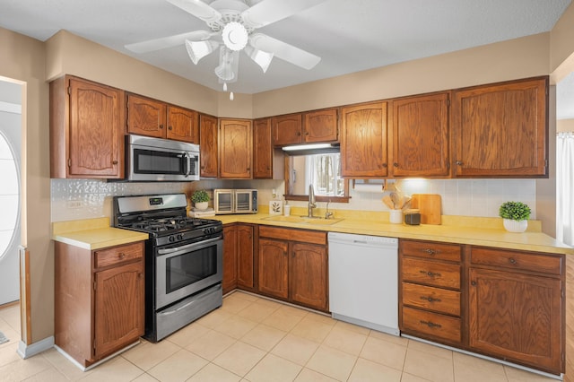 kitchen with decorative backsplash, appliances with stainless steel finishes, ceiling fan, sink, and light tile patterned floors