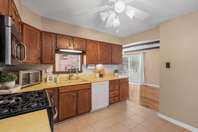 kitchen with ceiling fan, sink, black range with gas stovetop, light hardwood / wood-style flooring, and white dishwasher