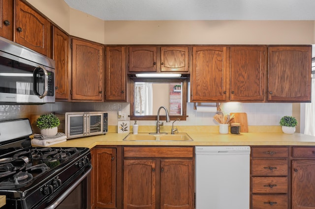 kitchen with backsplash, dishwasher, black gas stove, and sink