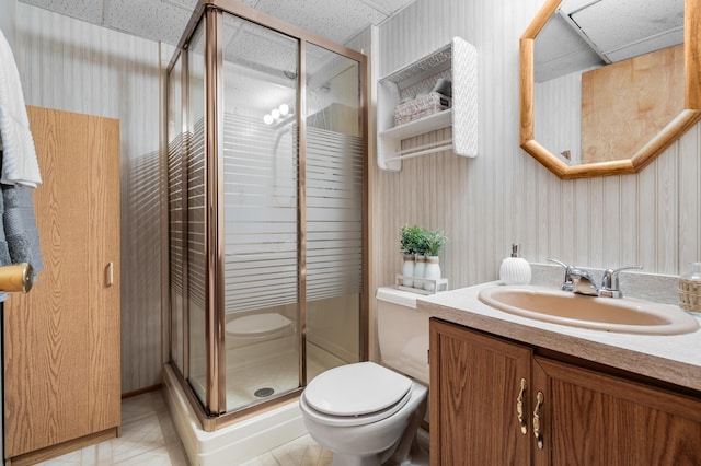 bathroom with tile patterned flooring, toilet, a paneled ceiling, vanity, and a shower with shower door