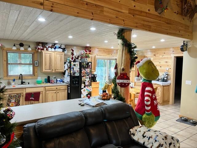 kitchen featuring light brown cabinets, black refrigerator, sink, light tile patterned floors, and wood ceiling