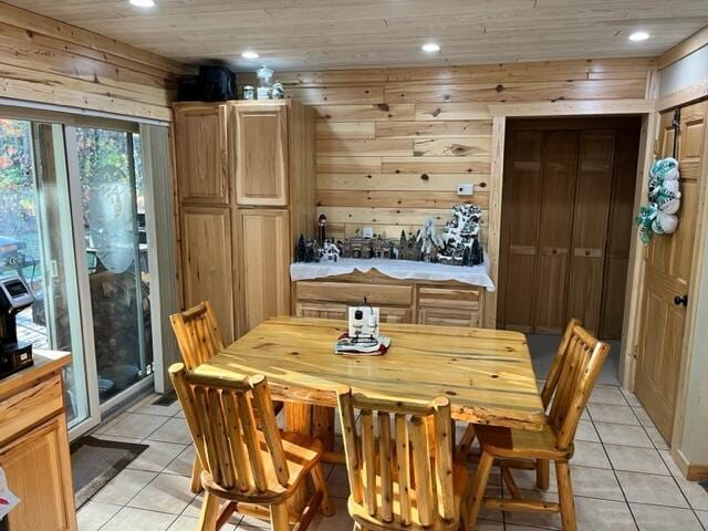 dining space with light tile patterned floors, wooden ceiling, and wood walls