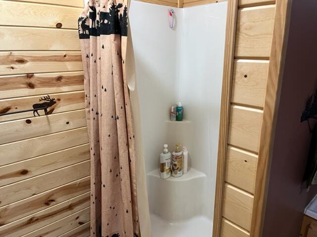 bathroom featuring walk in shower and wooden walls