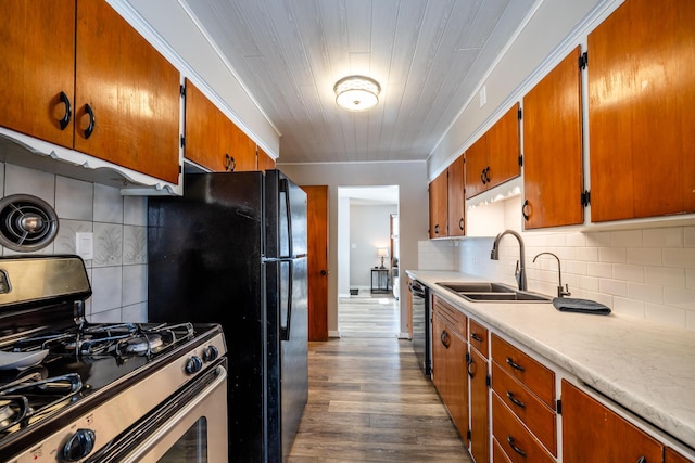 kitchen featuring sink, crown molding, decorative backsplash, wood-type flooring, and stainless steel appliances