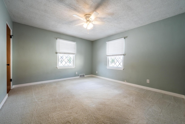 carpeted spare room with ceiling fan, a textured ceiling, and a wealth of natural light