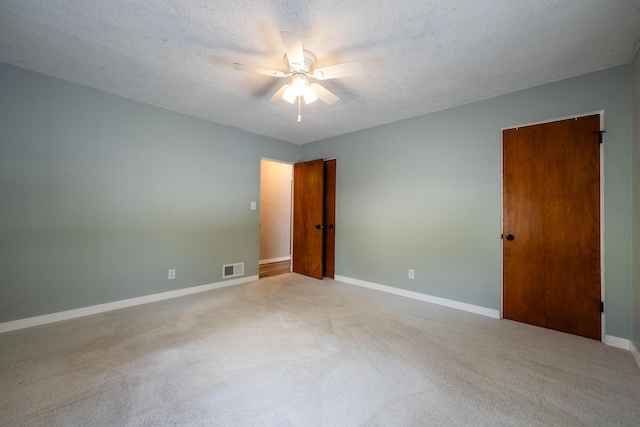 unfurnished room featuring ceiling fan, light colored carpet, and a textured ceiling