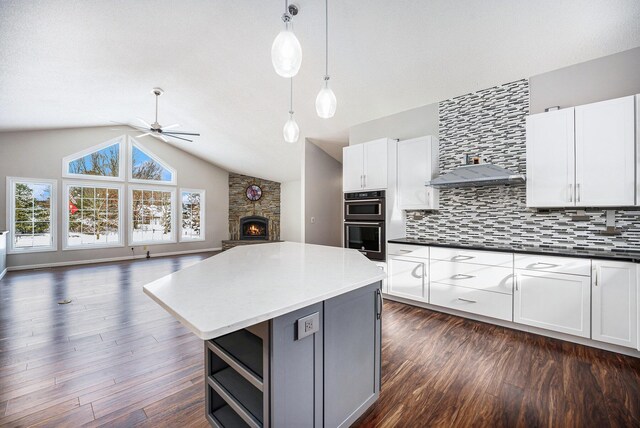 kitchen featuring double oven, white cabinetry, dark wood-type flooring, and pendant lighting