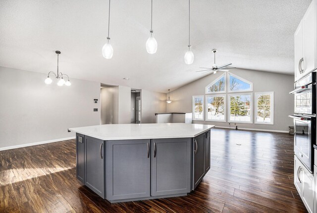 kitchen featuring gray cabinetry, hanging light fixtures, dark hardwood / wood-style flooring, vaulted ceiling, and white cabinets