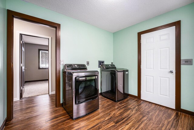 laundry room featuring a textured ceiling, separate washer and dryer, and dark wood-type flooring