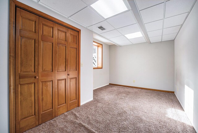 unfurnished bedroom with carpet, a closet, and a drop ceiling