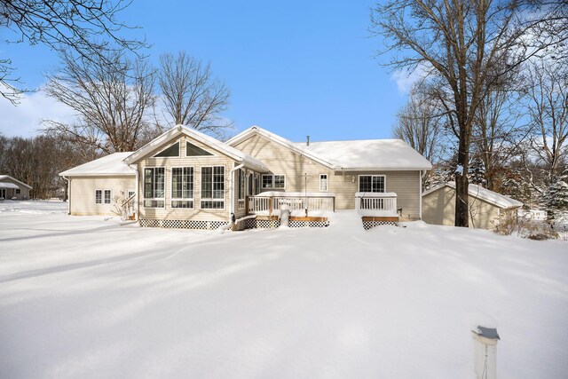 snow covered back of property featuring an outdoor structure and a wooden deck