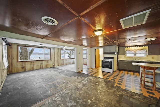 kitchen featuring gray cabinetry, wood walls, white range with gas stovetop, and sink