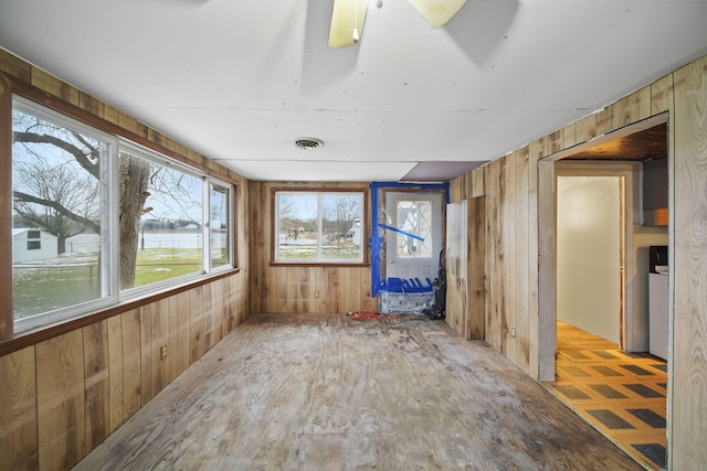 unfurnished sunroom featuring a water view, a wealth of natural light, and ceiling fan