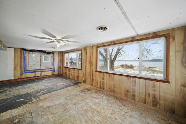 unfurnished room with ceiling fan and wood walls