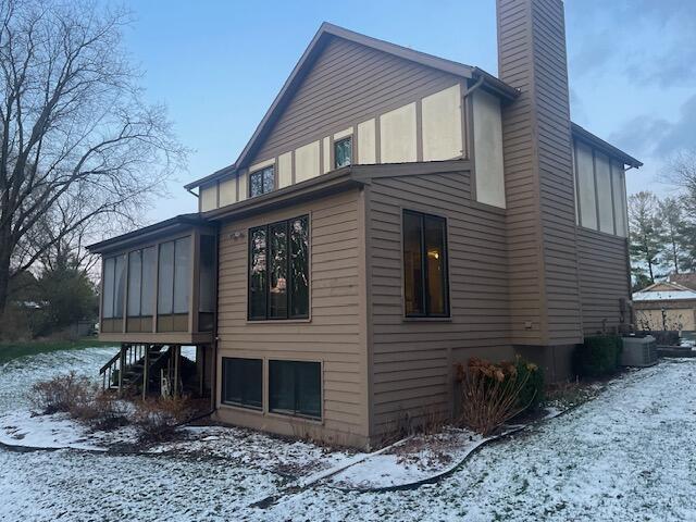 snow covered property with a sunroom and cooling unit