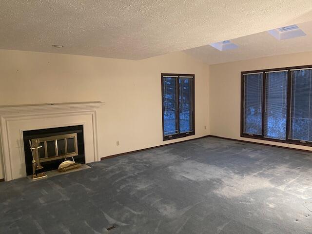 unfurnished living room with dark colored carpet and a textured ceiling