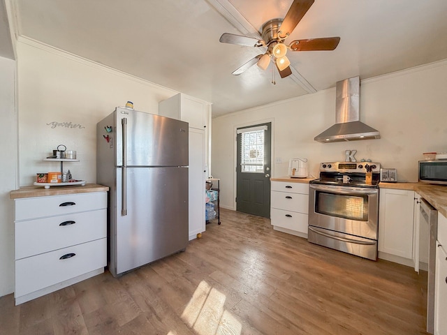 kitchen with white cabinets, crown molding, wall chimney exhaust hood, light hardwood / wood-style floors, and stainless steel appliances