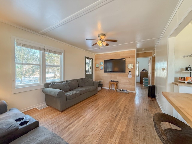 living room with ceiling fan, ornamental molding, and light wood-type flooring