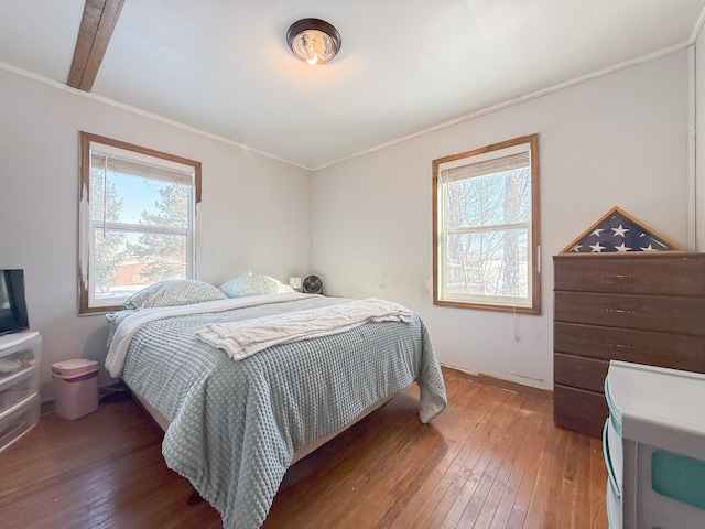 bedroom with beam ceiling, multiple windows, and hardwood / wood-style floors