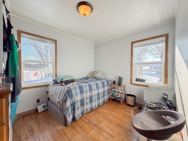 bedroom with light hardwood / wood-style flooring, multiple windows, and ornamental molding