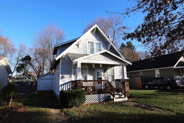 bungalow with a front yard, a porch, a garage, and an outdoor structure