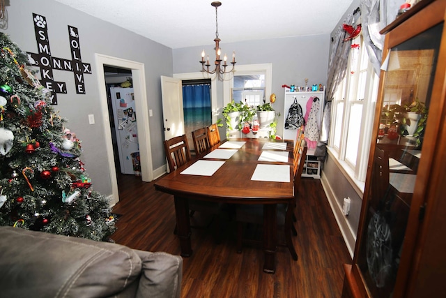 dining area featuring dark wood-type flooring and an inviting chandelier