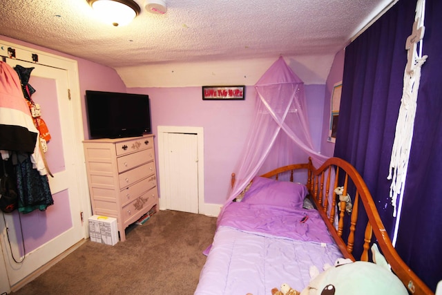 bedroom with a textured ceiling, dark carpet, and vaulted ceiling