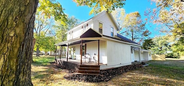 back of property with covered porch and a lawn