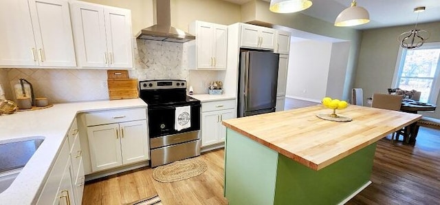 kitchen with white cabinets, wall chimney exhaust hood, pendant lighting, and stainless steel appliances