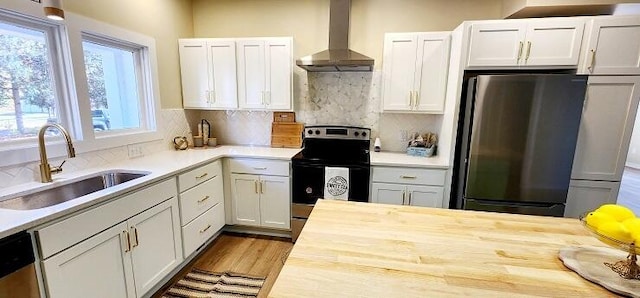 kitchen featuring appliances with stainless steel finishes, backsplash, wall chimney exhaust hood, sink, and white cabinetry