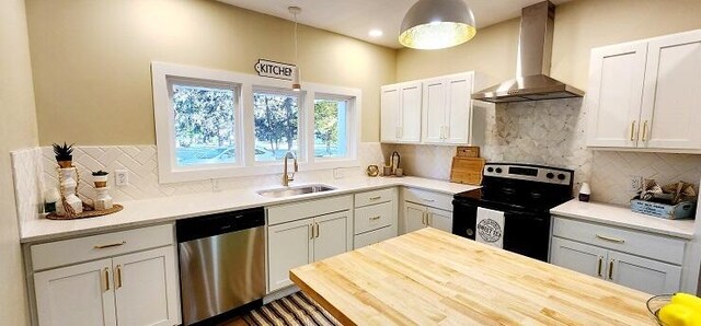 kitchen featuring sink, hanging light fixtures, stainless steel appliances, wall chimney range hood, and backsplash